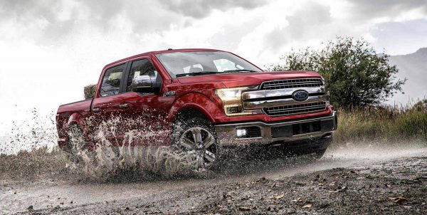 A red 2018 Ford F-150 driving through muddy water
